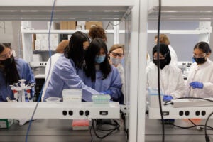 Lab workers teaching the SPIN Girls Fellows how to work at a scientific bench