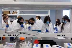 Lab workers teaching the SPIN Girls Fellows how to work at a scientific bench